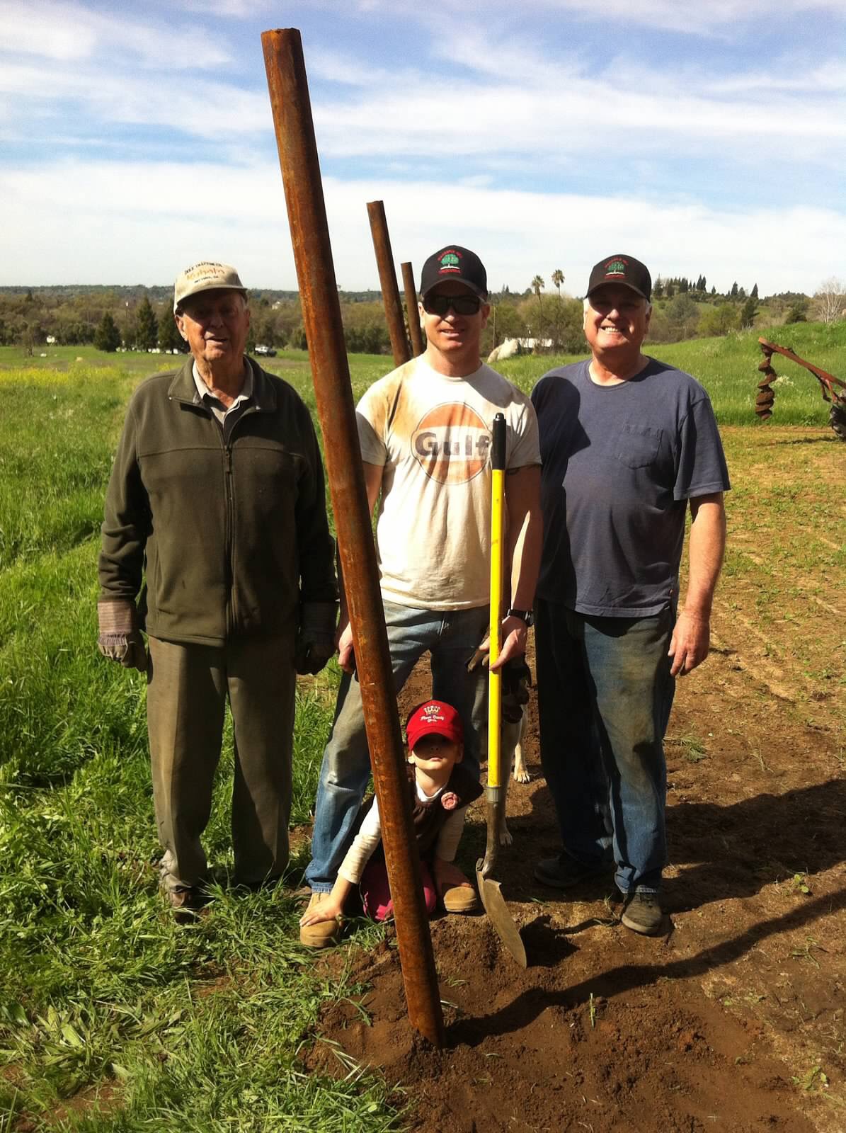 3 men standing by a post, child by their feet