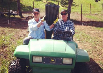 two men on a tractor with posts for planting the vineyard
