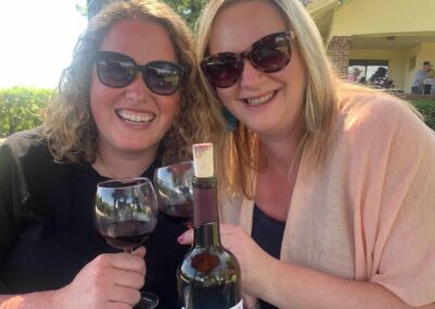 Two ladies with glasses of red wine and wine bottle